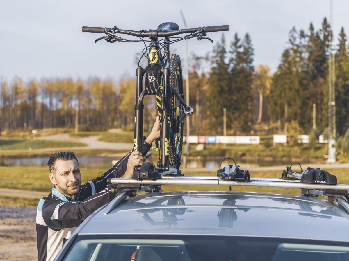 A serious looking man fixes his MTB bike to the roof rack of his car
