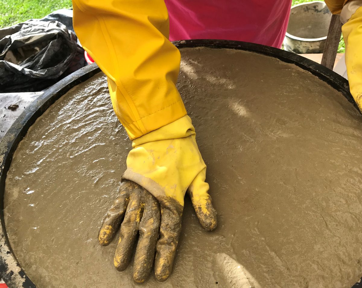 Smoothing a concrete mould wearing a pair of yellow rubber gloves. Try some concrete casting yourself with Pia at Meet the Locals