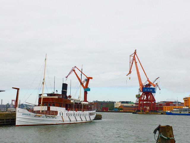 The white hulled steamboat, Bohuslän, is tied up at the quayside in Gothenburg harbour with some old cranes across the river in the background. Get to know more about Gothenburg with a guided tour from Meet the Locals