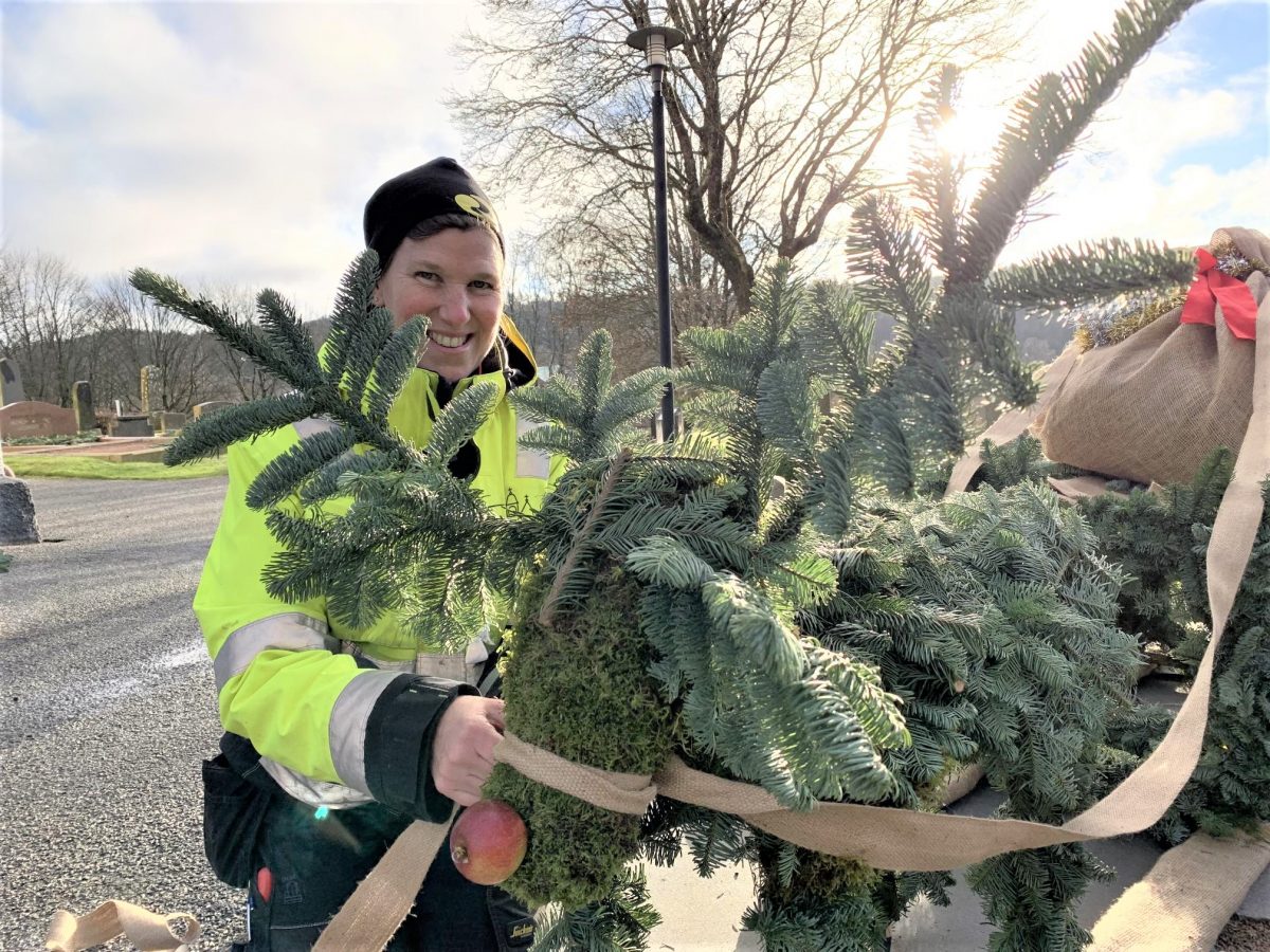 Maria is wearing a high viz jacket and holding pieces of fir tree. She looks happy in her work encouraging biodiversity in a cemetery in West Sweden and welcoming visitors who find her through Meet the Locals